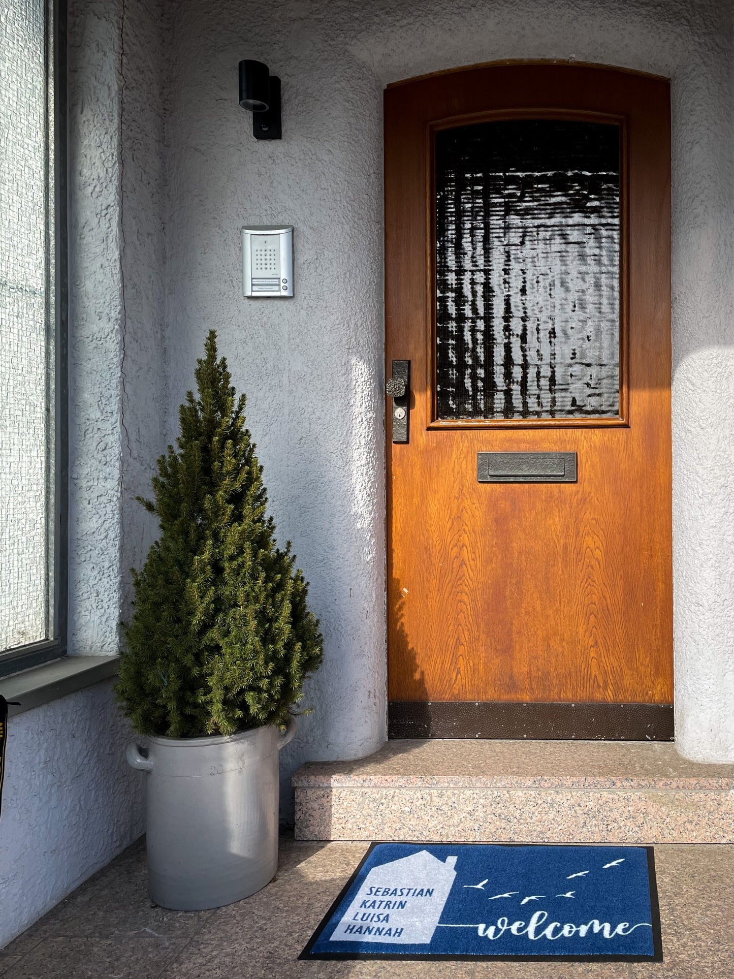 blaue Fußmatte vor alter Haustür mit Aufschrift welcome