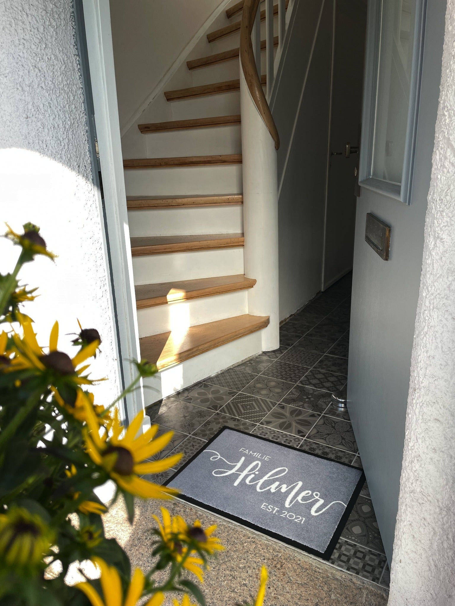 Graue Haustür mit grauer personalisierter Fußmatte